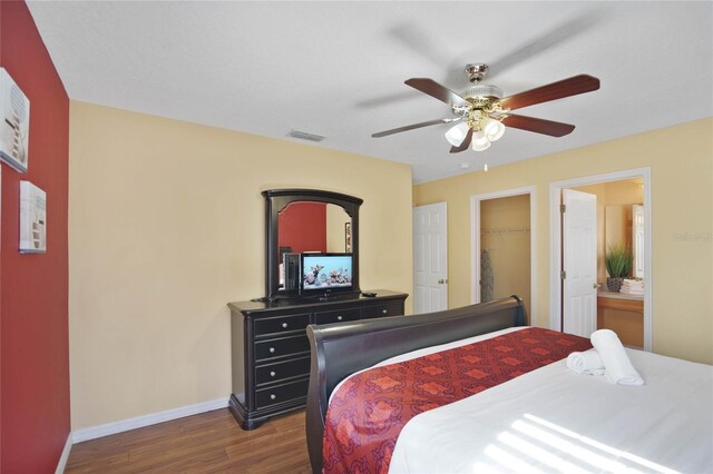 bedroom with ensuite bath, ceiling fan, dark wood-type flooring, a spacious closet, and a closet