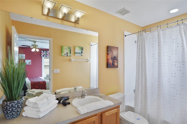 full bathroom featuring ceiling fan, a textured ceiling, toilet, shower / tub combo with curtain, and vanity