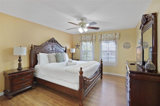 bedroom with ceiling fan, light wood-type flooring, and a textured ceiling