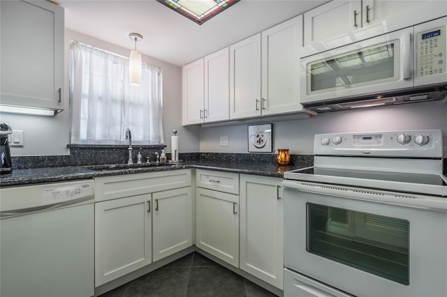 kitchen featuring white appliances, white cabinets, sink, dark stone countertops, and decorative light fixtures