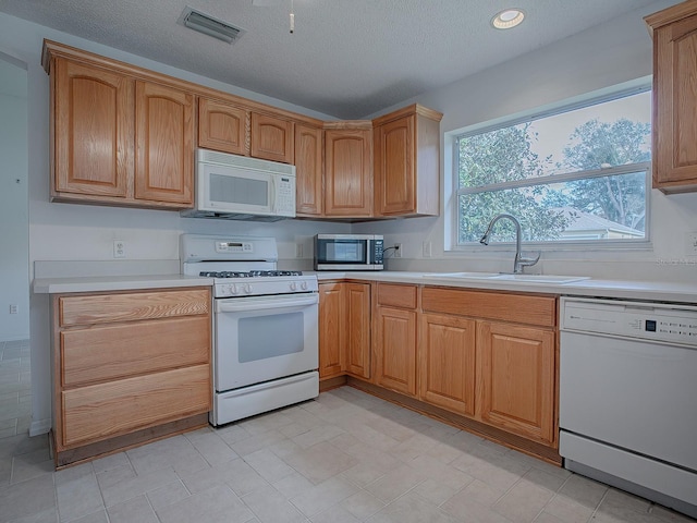 kitchen featuring a textured ceiling, white appliances, and sink