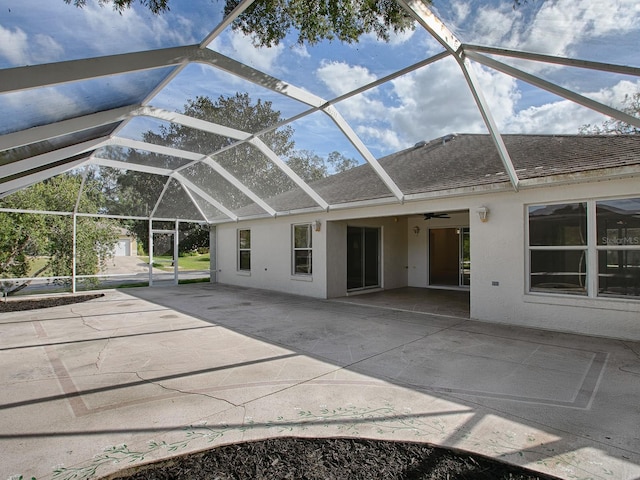 exterior space featuring glass enclosure, ceiling fan, and a patio area