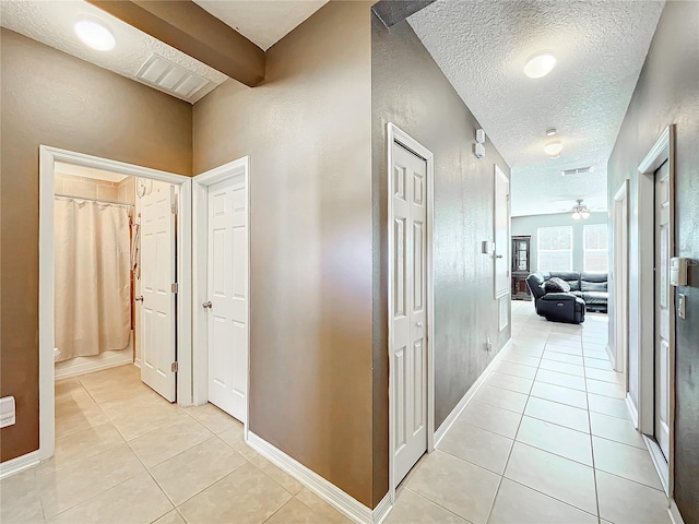 corridor featuring light tile patterned floors, a textured ceiling, and visible vents