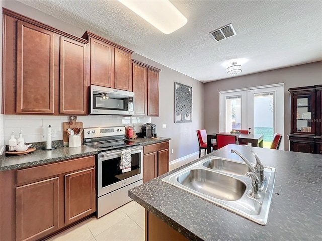 kitchen with visible vents, dark countertops, appliances with stainless steel finishes, french doors, and a sink