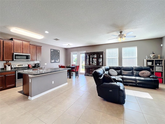 kitchen featuring stainless steel appliances, dark countertops, open floor plan, and light tile patterned floors