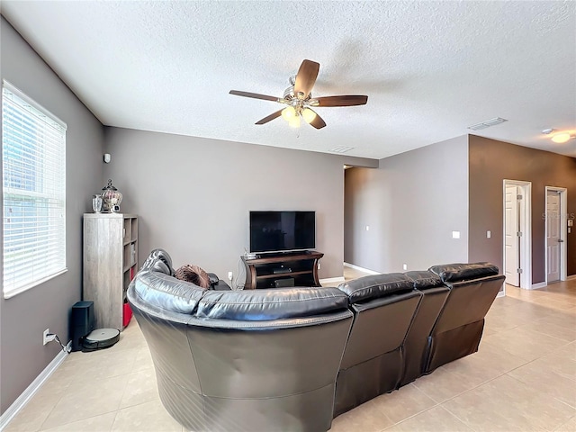 living room featuring visible vents, light tile patterned flooring, ceiling fan, a textured ceiling, and baseboards