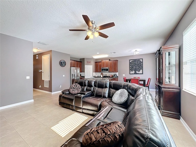 living room featuring light tile patterned floors, visible vents, baseboards, and a textured ceiling