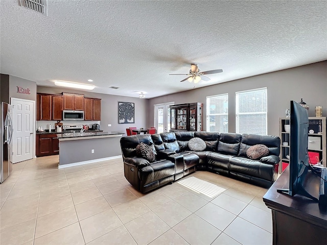 living room with visible vents, ceiling fan, a textured ceiling, and light tile patterned floors