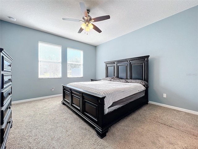 bedroom with a ceiling fan, light carpet, a textured ceiling, and baseboards