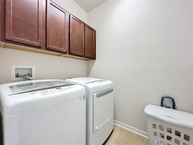 clothes washing area with cabinet space, washing machine and dryer, light tile patterned floors, and baseboards