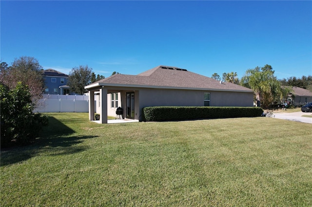 view of side of home with a yard, a patio area, fence, and stucco siding