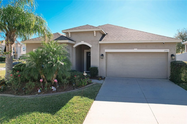 view of front of house with roof with shingles, stucco siding, concrete driveway, an attached garage, and a front yard