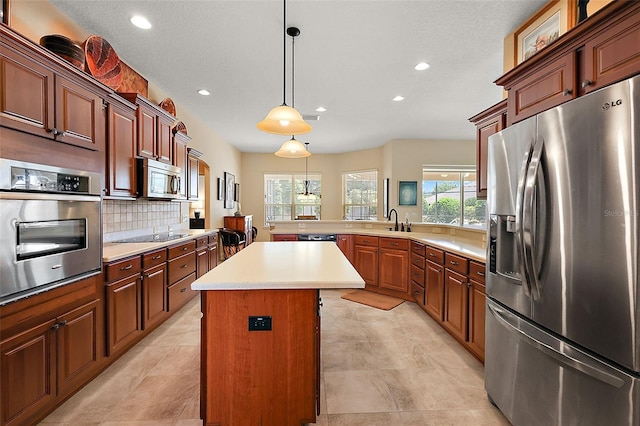 kitchen featuring tasteful backsplash, stainless steel appliances, sink, a kitchen island, and hanging light fixtures