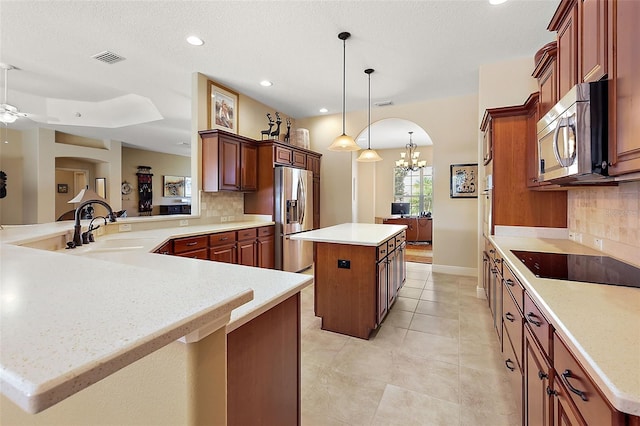 kitchen with a center island, backsplash, sink, appliances with stainless steel finishes, and kitchen peninsula