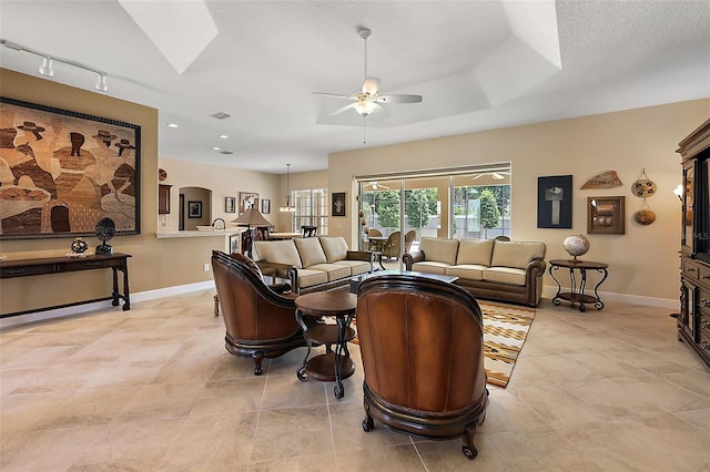 tiled living room featuring a textured ceiling, rail lighting, and ceiling fan