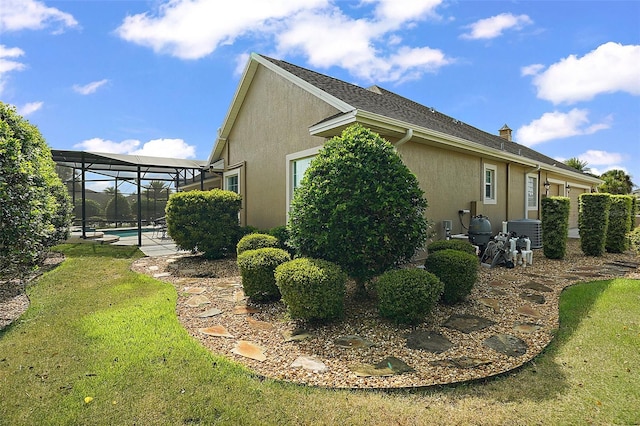 view of home's exterior featuring central AC, glass enclosure, and a lawn