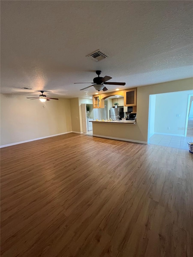 unfurnished living room with wood-type flooring and a textured ceiling