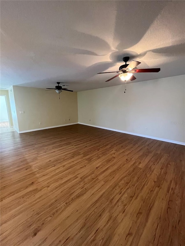 unfurnished room featuring ceiling fan, dark wood-type flooring, and a textured ceiling