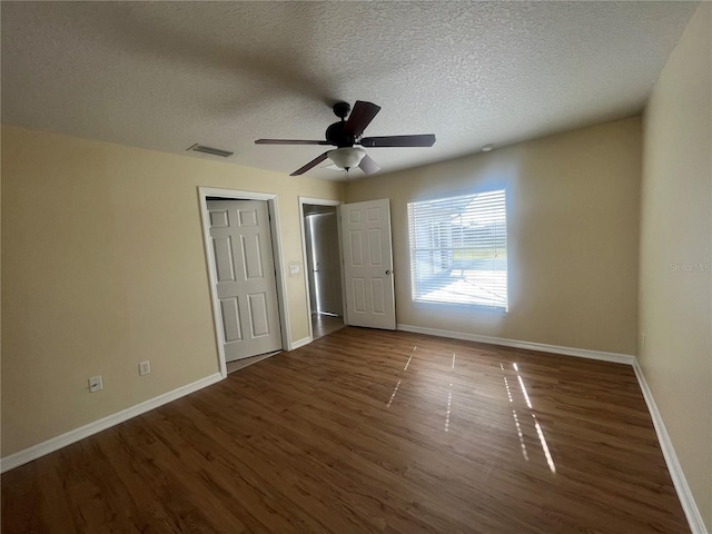 unfurnished bedroom with ceiling fan, dark hardwood / wood-style flooring, and a textured ceiling