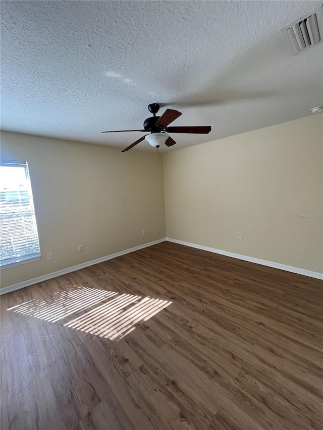 empty room with a textured ceiling, ceiling fan, and dark hardwood / wood-style floors