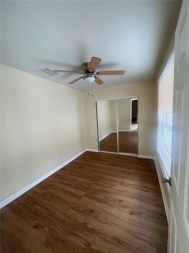 unfurnished bedroom featuring ceiling fan, a closet, and dark wood-type flooring