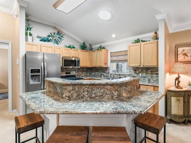 kitchen with light stone countertops, vaulted ceiling, decorative backsplash, a kitchen island, and appliances with stainless steel finishes