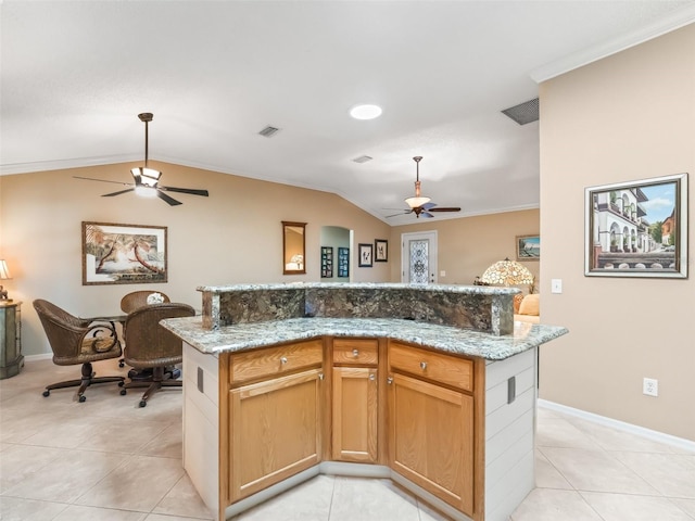 kitchen featuring a center island, lofted ceiling, crown molding, light stone countertops, and light tile patterned flooring