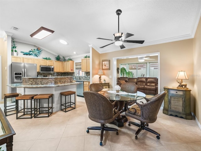 dining area featuring light tile patterned flooring, vaulted ceiling, and ornamental molding