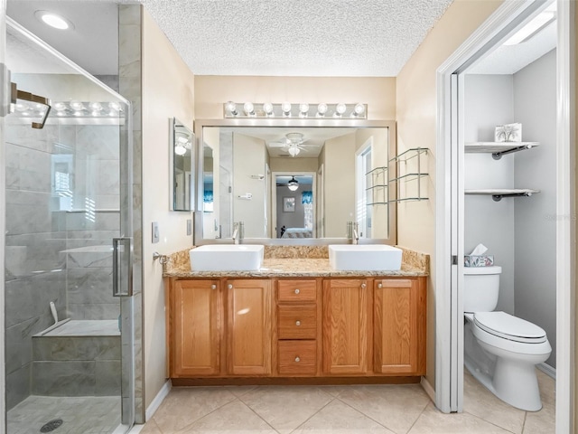 bathroom with tile patterned floors, walk in shower, vanity, ceiling fan, and toilet