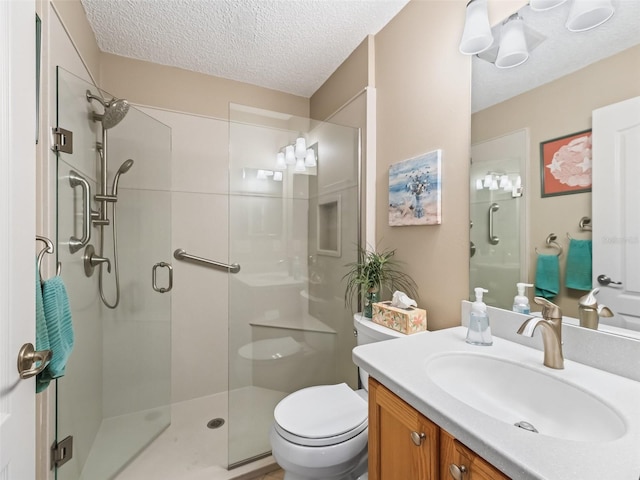 bathroom featuring a shower with door, vanity, a textured ceiling, and toilet