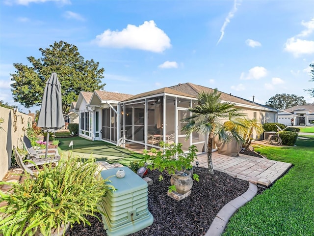 rear view of property featuring a sunroom, a yard, and a patio