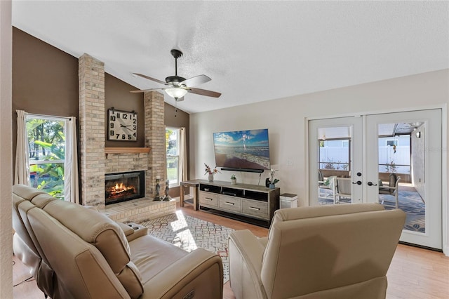 living room with ceiling fan, french doors, light hardwood / wood-style floors, a textured ceiling, and lofted ceiling