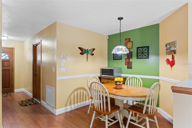 dining area featuring a textured ceiling and hardwood / wood-style flooring