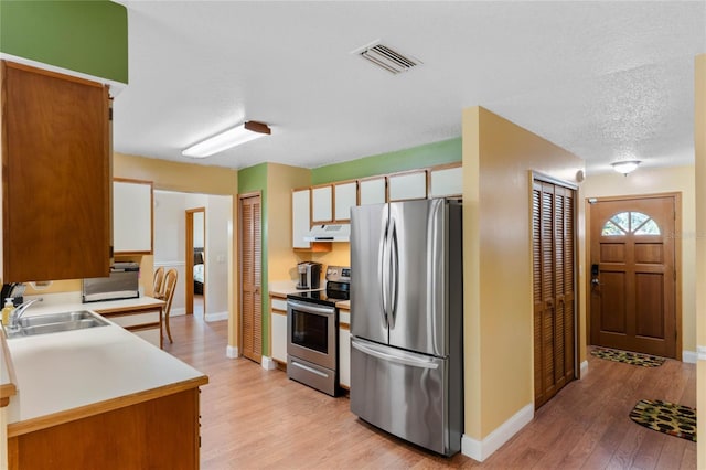 kitchen with stainless steel appliances, extractor fan, sink, light hardwood / wood-style flooring, and white cabinets