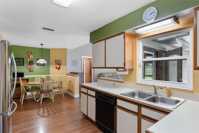 kitchen with sink, decorative light fixtures, white cabinets, black dishwasher, and stainless steel refrigerator