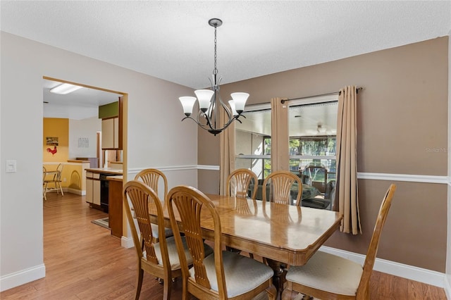 dining room with a chandelier, a textured ceiling, and light hardwood / wood-style flooring