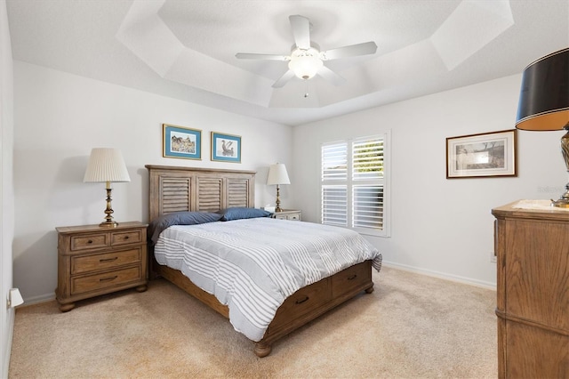 carpeted bedroom featuring a raised ceiling and ceiling fan