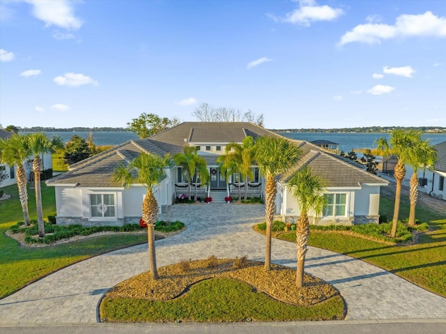 ranch-style house featuring covered porch, a water view, and a front yard