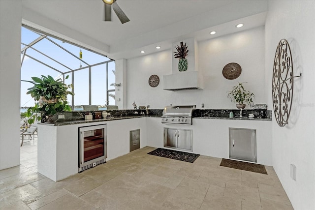 kitchen with white cabinets, wall chimney exhaust hood, kitchen peninsula, and wine cooler