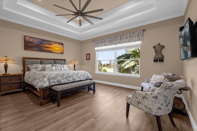 bedroom with a tray ceiling, crown molding, ceiling fan, and hardwood / wood-style flooring