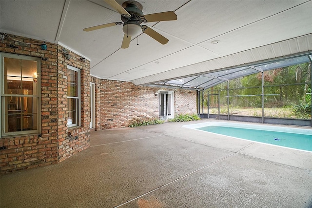 view of swimming pool with glass enclosure, ceiling fan, and a patio area