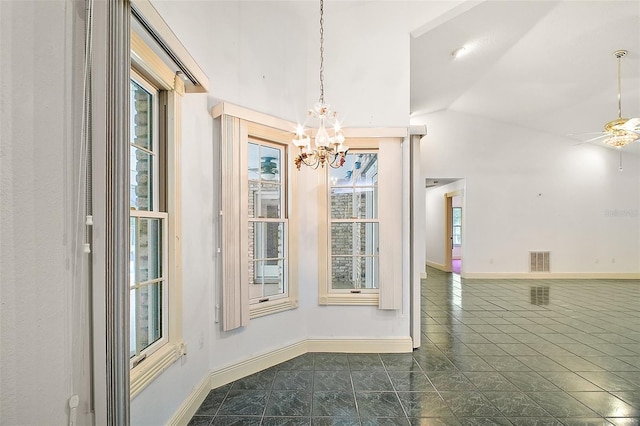 unfurnished dining area with dark tile patterned flooring, ceiling fan with notable chandelier, vaulted ceiling, and plenty of natural light