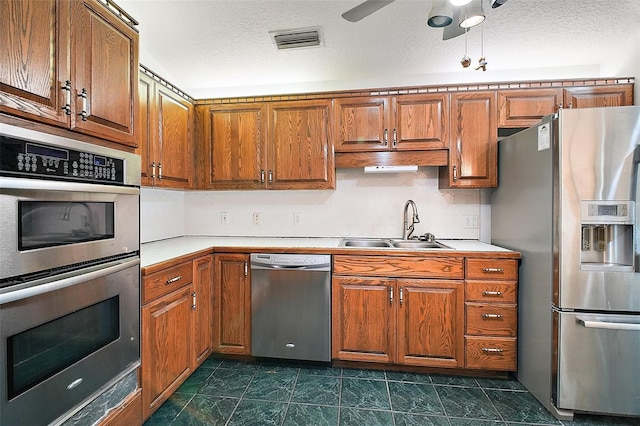 kitchen featuring ceiling fan, sink, stainless steel appliances, and a textured ceiling