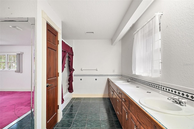 bathroom featuring a textured ceiling, vanity, and tile walls