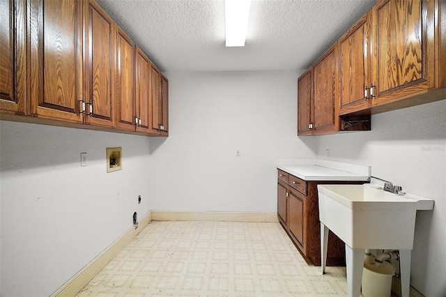 washroom with washer hookup, cabinets, and a textured ceiling