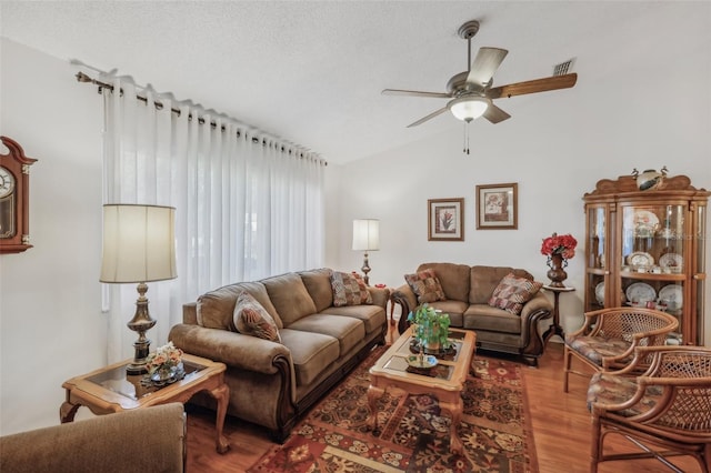 living room with a textured ceiling, ceiling fan, wood-type flooring, and lofted ceiling