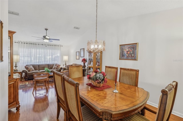 dining space featuring ceiling fan with notable chandelier and hardwood / wood-style flooring