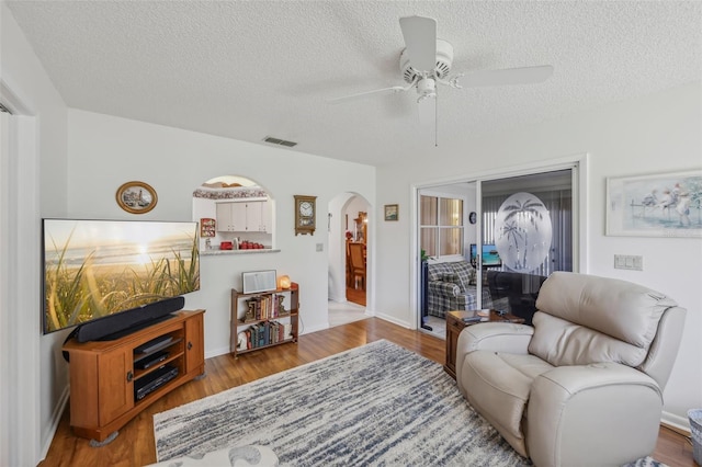 living room with ceiling fan, wood-type flooring, and a textured ceiling