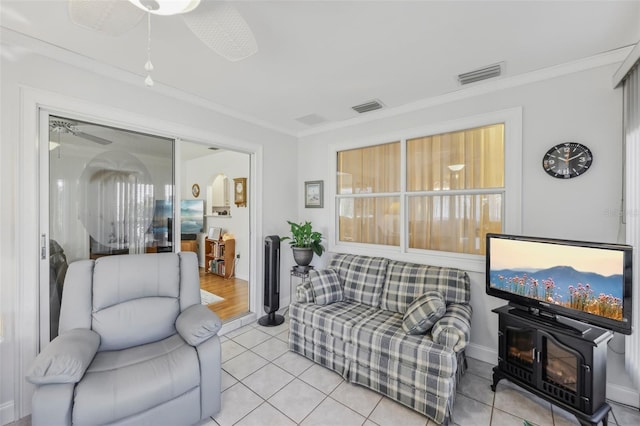 tiled living room with ceiling fan, a wood stove, and crown molding