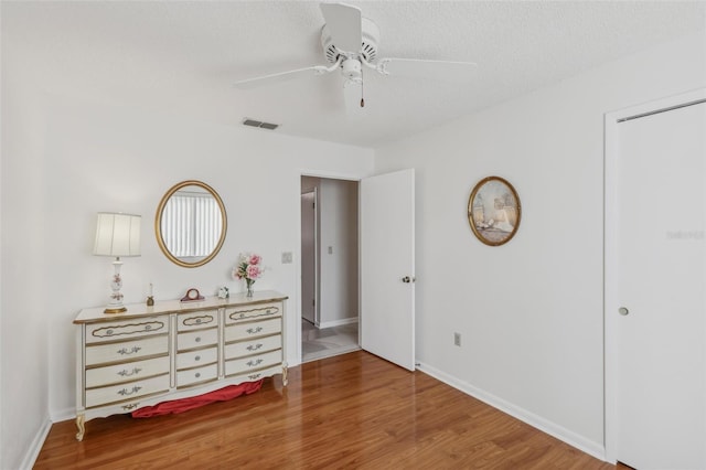 unfurnished bedroom with ceiling fan, wood-type flooring, and a textured ceiling